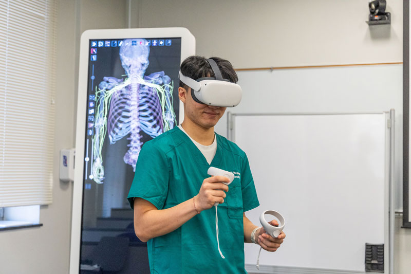 Joe Song ‘26 uses the nursing school’s virtual reality headset as a facet of his high-tech training. These tools include the Anatomage simulation interface, designed to be either a table for observing a virtual body or as an upright classroom instruction tool.