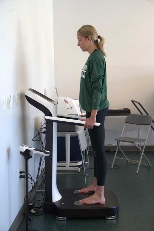 Female student standing on an InBody machine