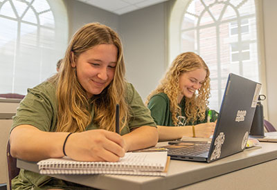 Two students taking notes during class