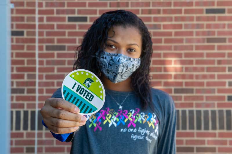 Student posing with a Titan "I Voted" sticker