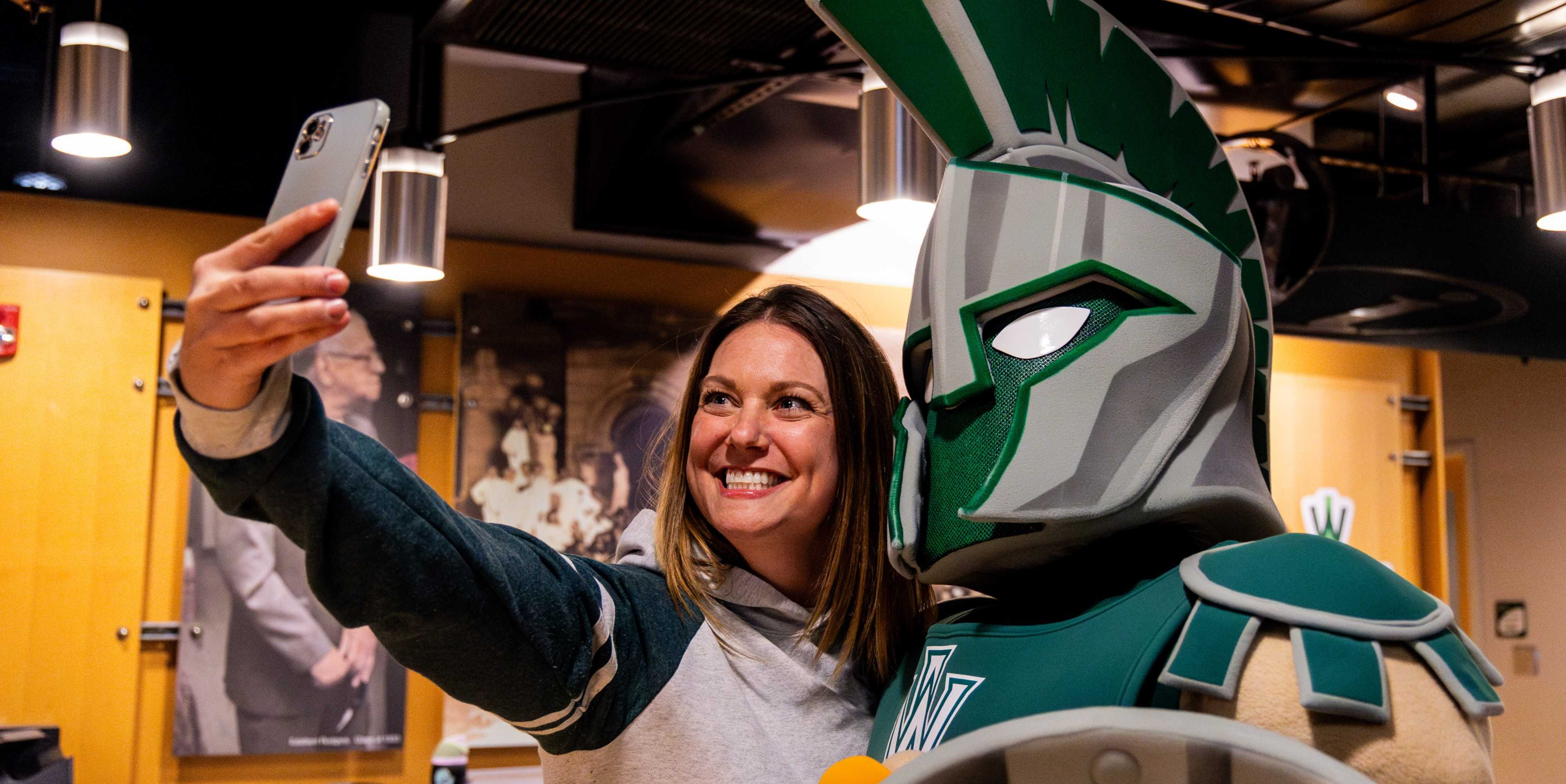 Woman holding her phone out to take selfie with mascot Tommy the Titan