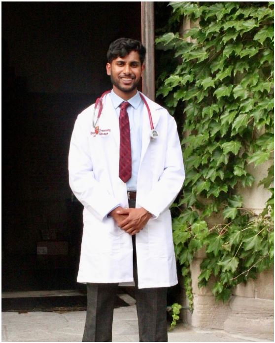 Manish Pathuri smiles towards camera while wearing a white lab coat
