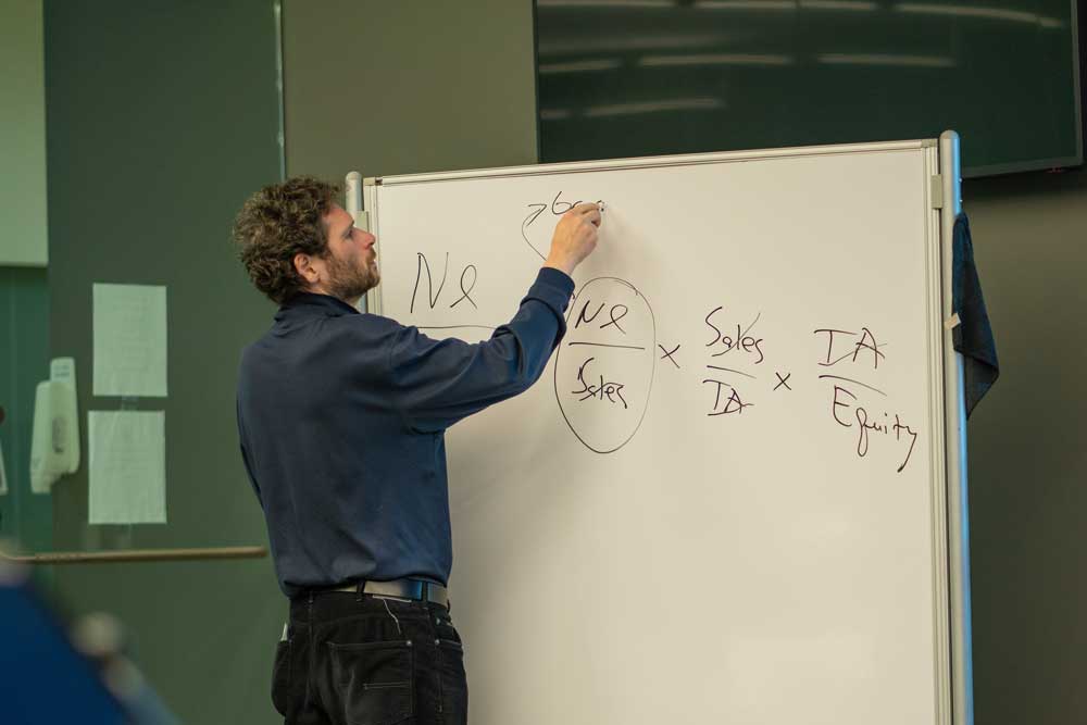 Professor Munenzon writes on a whiteboard during a finance class in the Bloomberg Finance Lab.