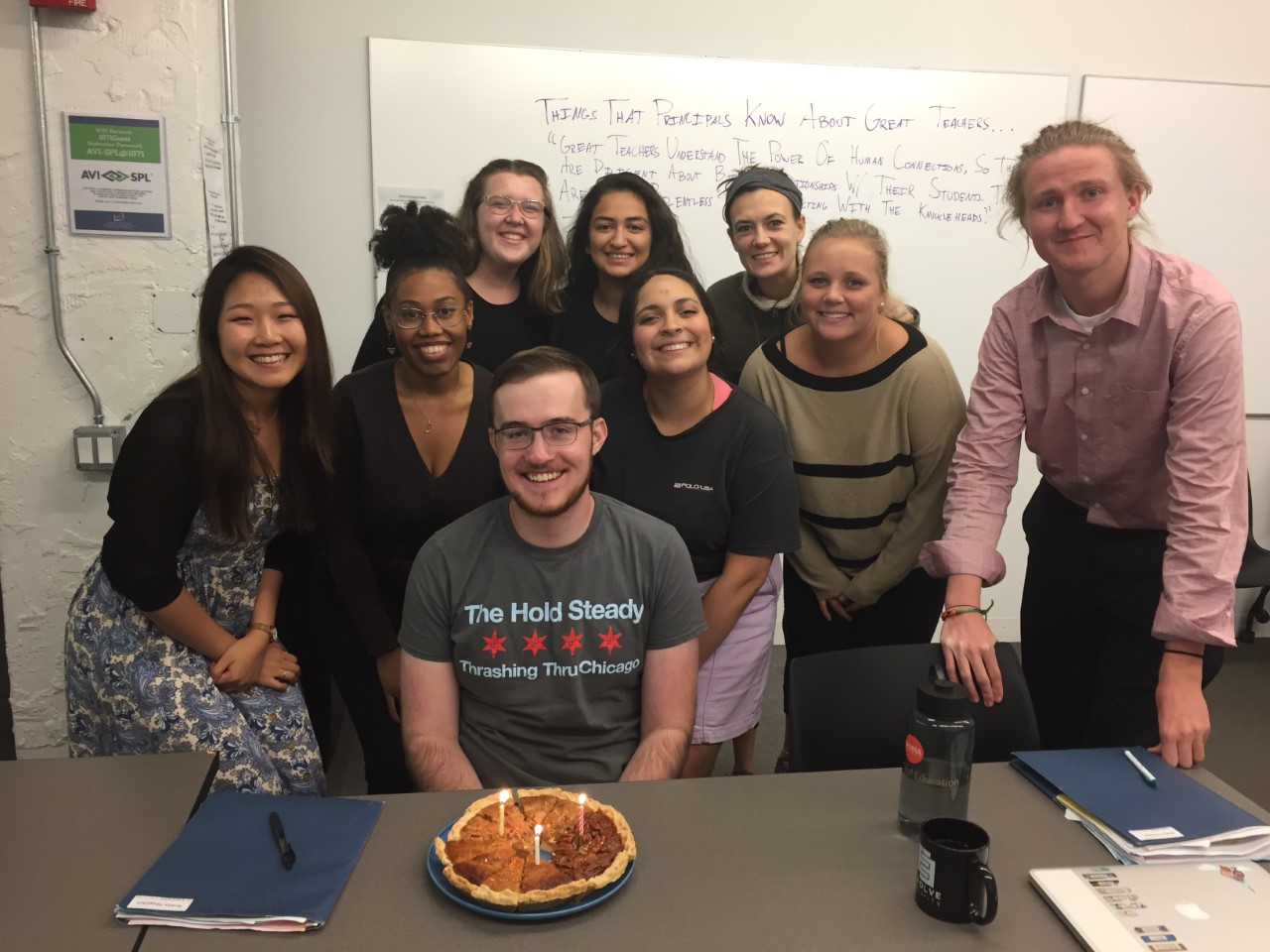 A group of students celebrating a birthday with a birthday pie