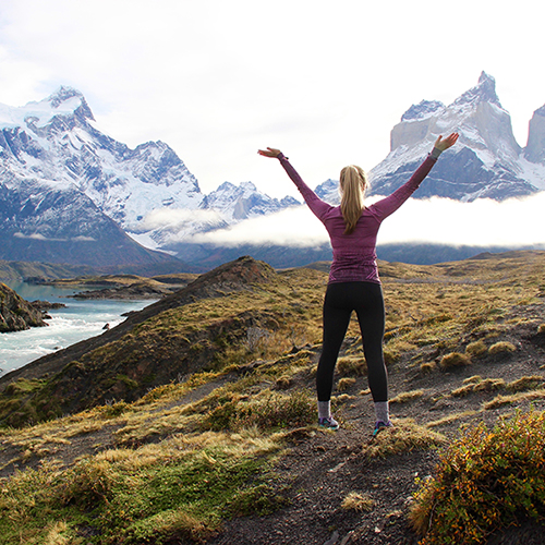 Kaitlyn on the top of a mountain with arms outstretched