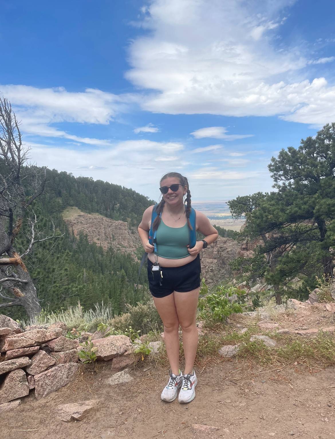 Female student wearing a backpack smiling to the camera with mountainous background