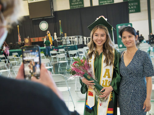 A fraternity member and her family stand for a photo at graduation.