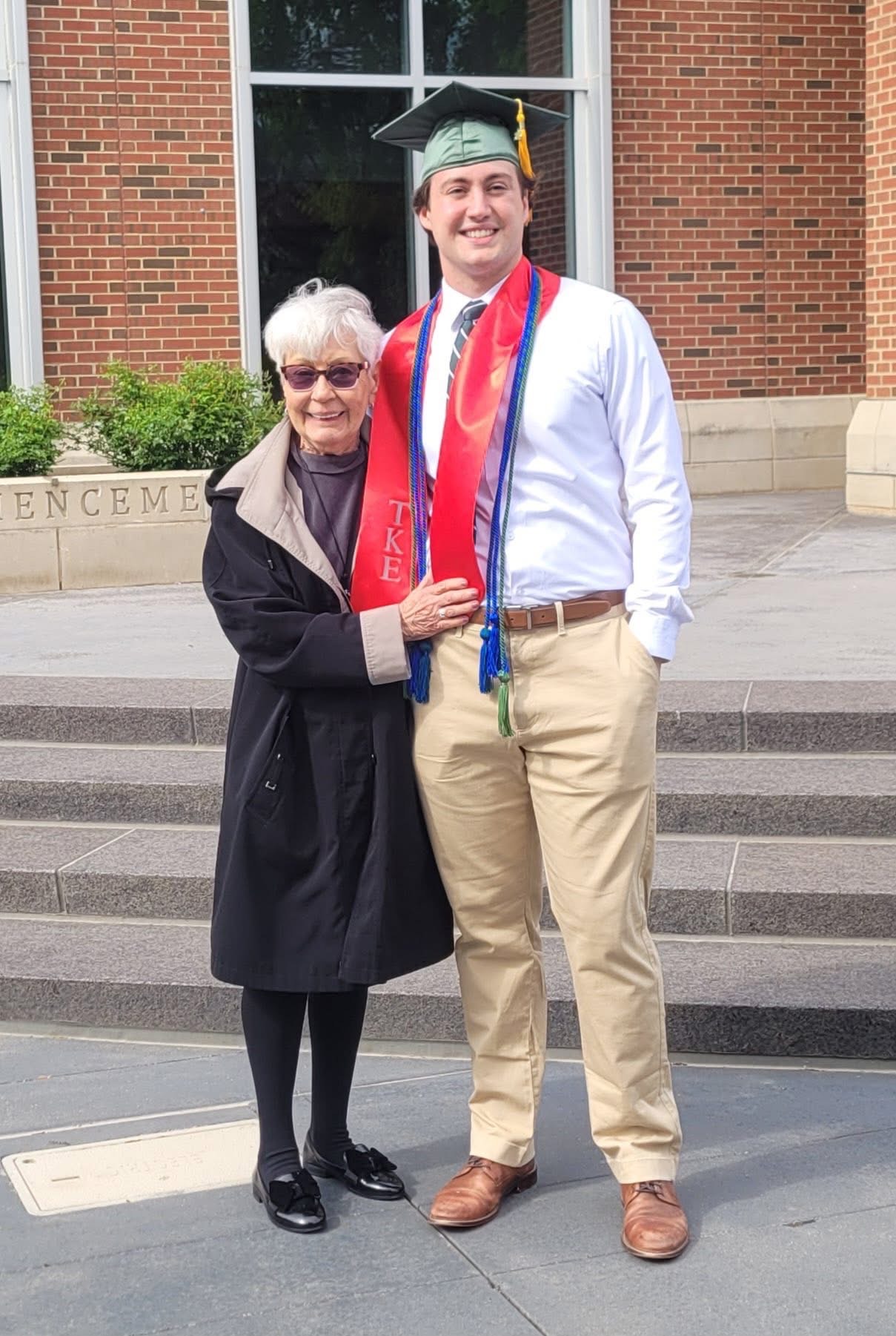 A fraternity member and his family stand for a photo at graduation.