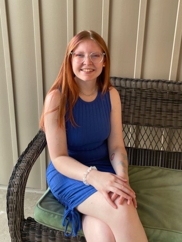 Female college student sitting on a patio chair and smiling