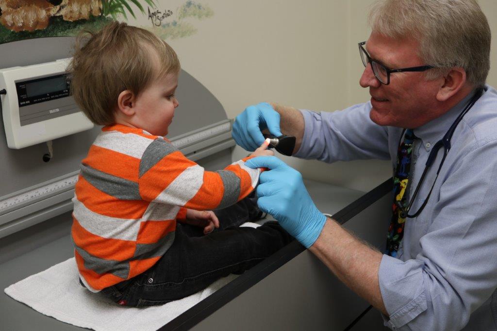 Dr. Raymond Davis ’80 meets with a young patient at his general pediatric practice.