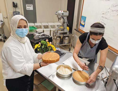 Slevin (right) and Amber Shahzad (left) bake cakes in the C. Love Cookie Project kitchen.