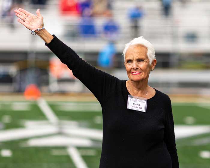 Carol Willis ’68 waves to the crowd attending Illinois Wesleyan’s 2021 Homecoming football game. Willis has provided opportunities for IWU students through support of women’s athletics.