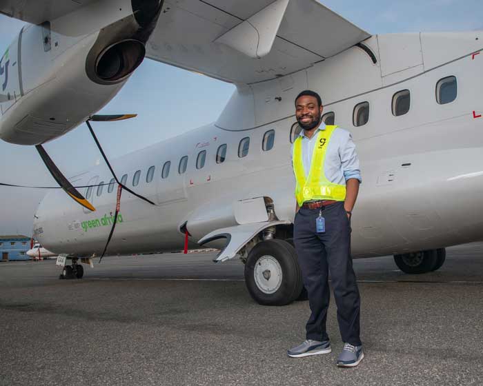 Babawande Afolabi ’10 poses beside one of the aircraft in the fleet of Green Africa Airways, the airline he founded.