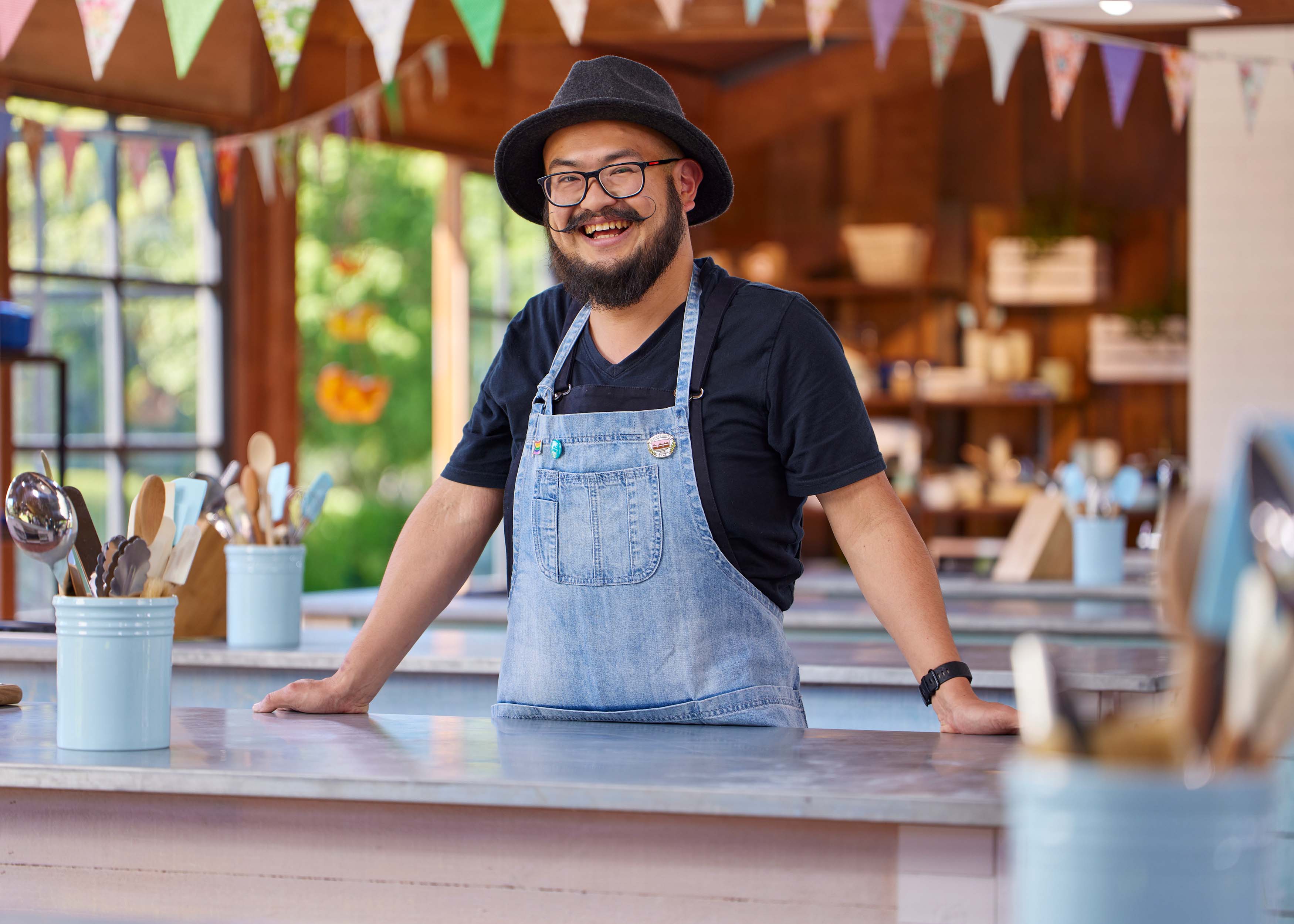 Nurman Noor standing at baking counter smiling