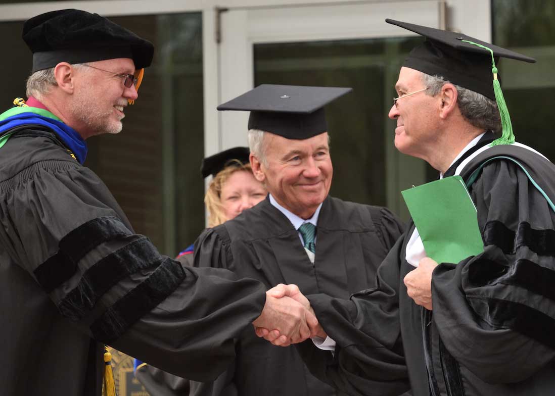 Provost Mark Brodl shakes hands with Commencement Speaker Dr. William Farrar '71