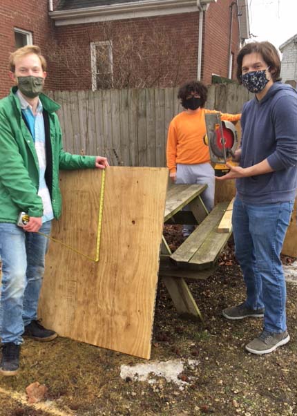 Students work on cover for cistern at garden