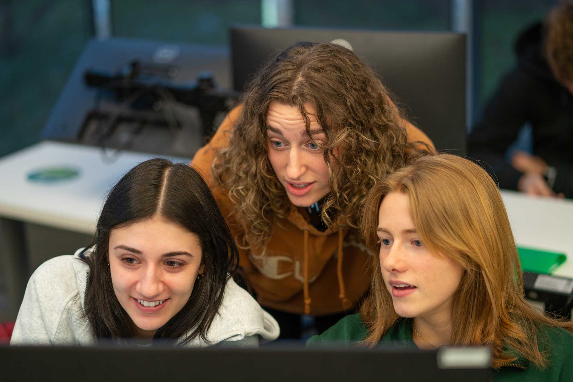 Three students gather around Bloomberg terminal to complete assignment