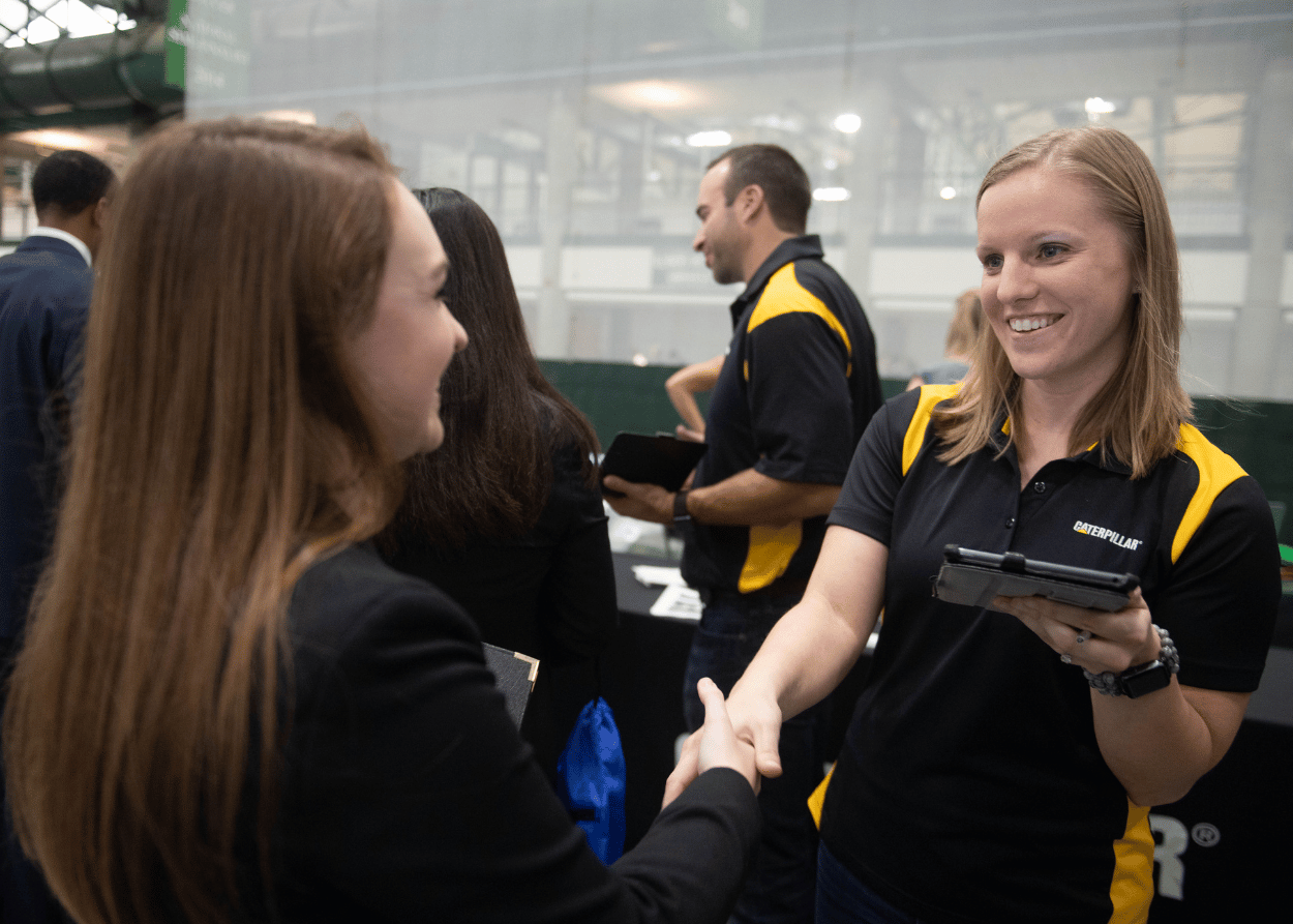 Employee with Caterpillar shakes hand with IWU student