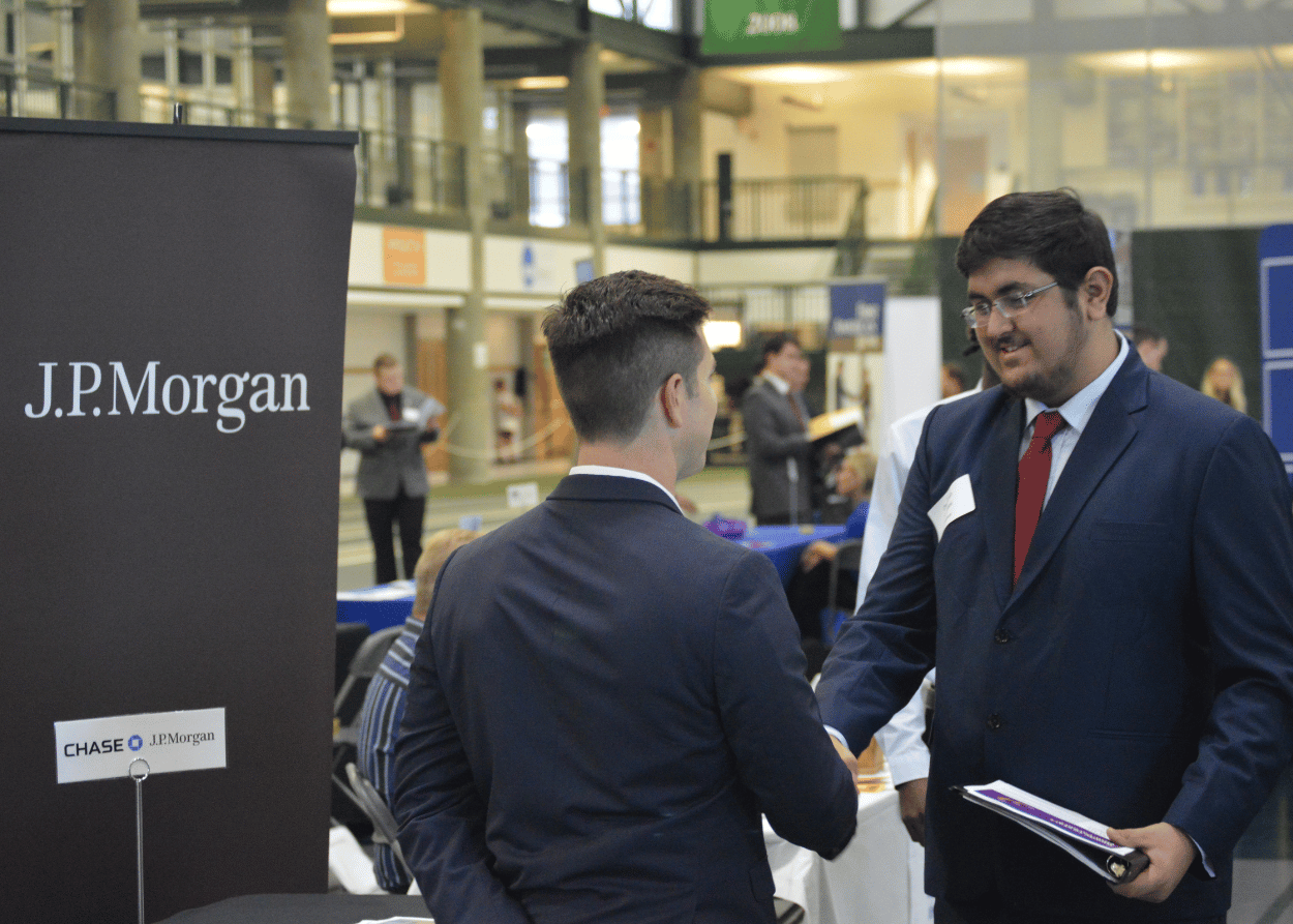 Student shaking hands with a JP Morgan representative at a recent Illinois Wesleyan career fair