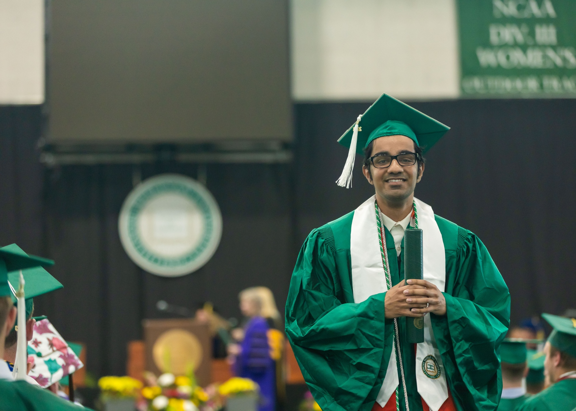 Student holding diploma after crossing commencement stage at Illinois Wesleyan