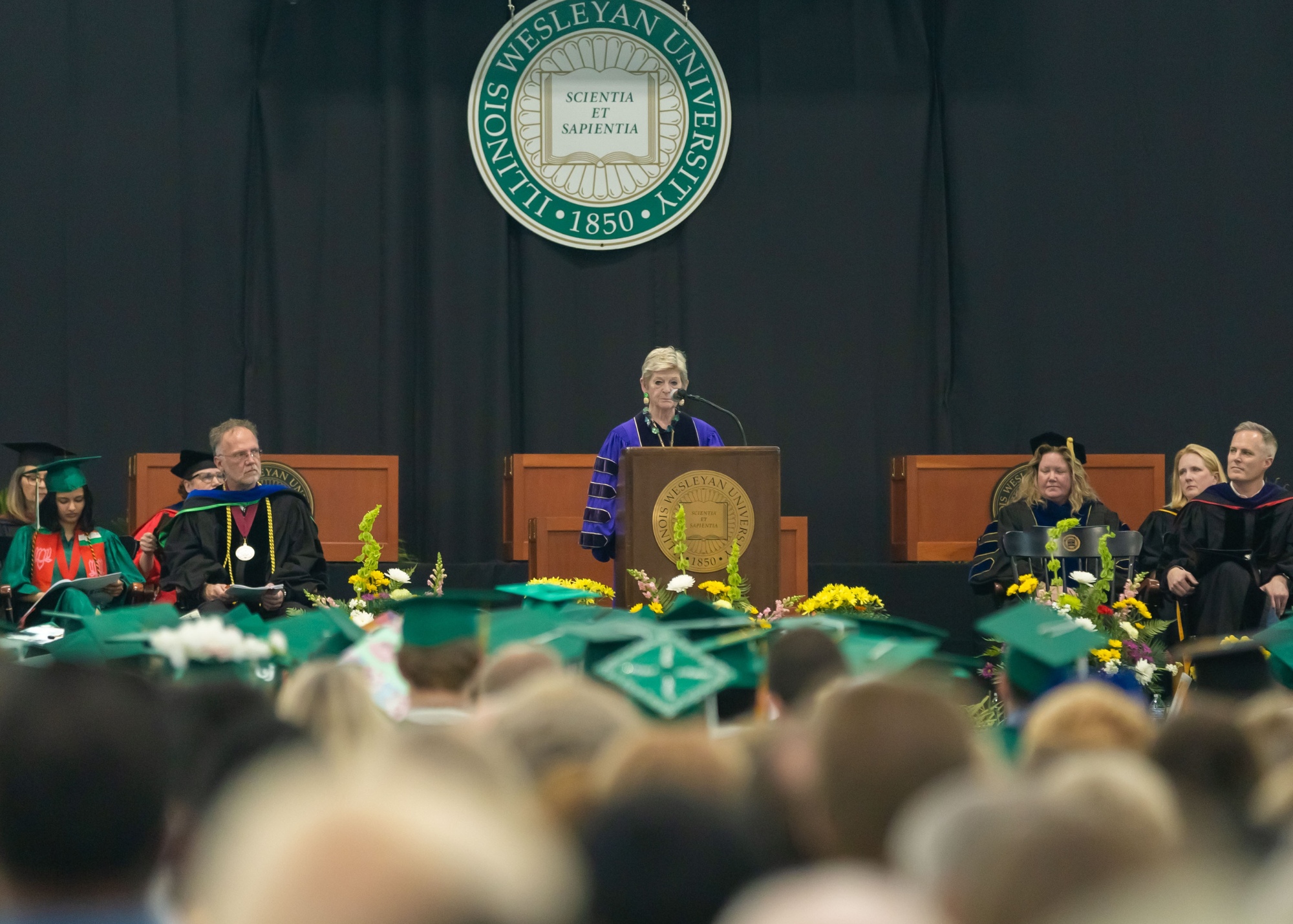 Illinois Wesleyan president speaking on stage at commencement