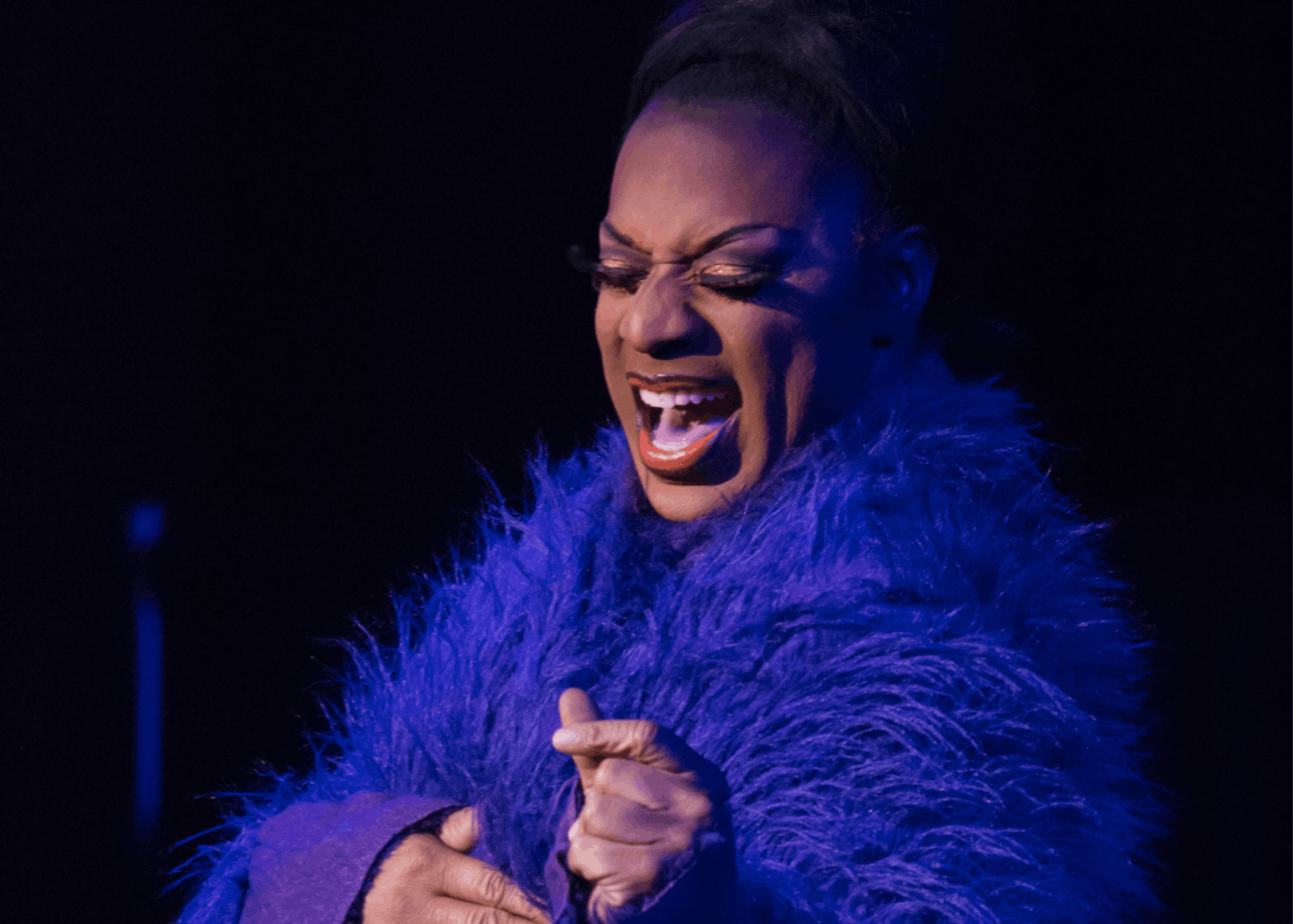 Performer signing on stage during Charity Drag Show at IWU