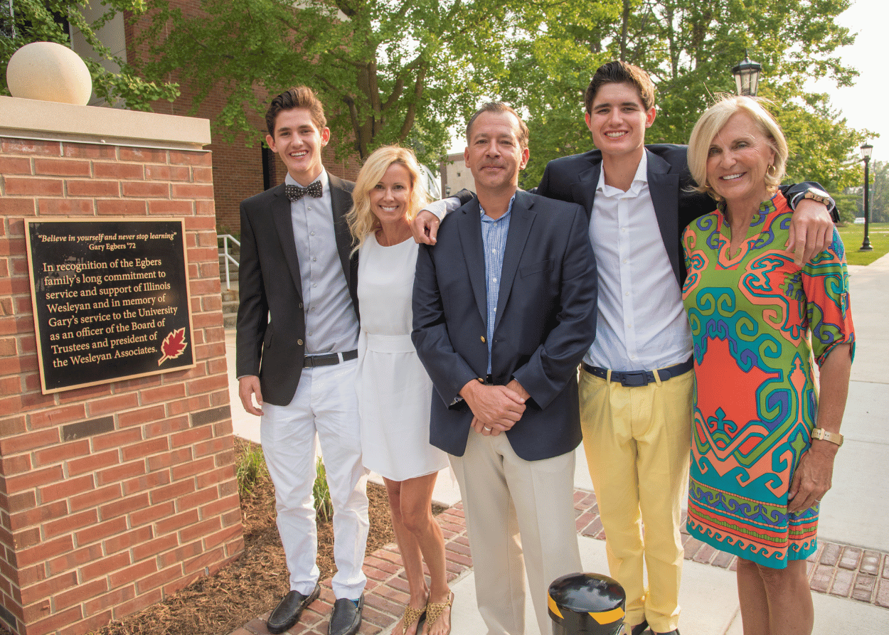 Family of Gary Egbers stand next to a plaque during the dedication of Egbers Quad on IWU campus