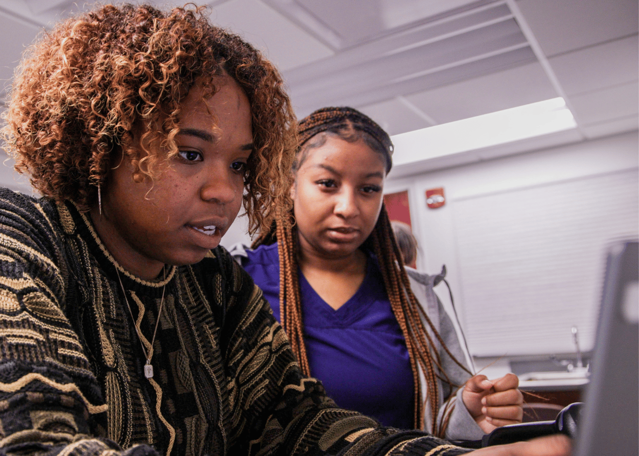 Two nursing students review patient information on a computer while doing an escape room activity
