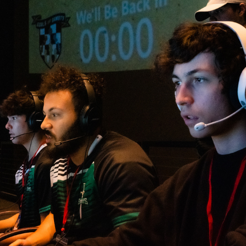 Students with headsets playing on a row of compuers