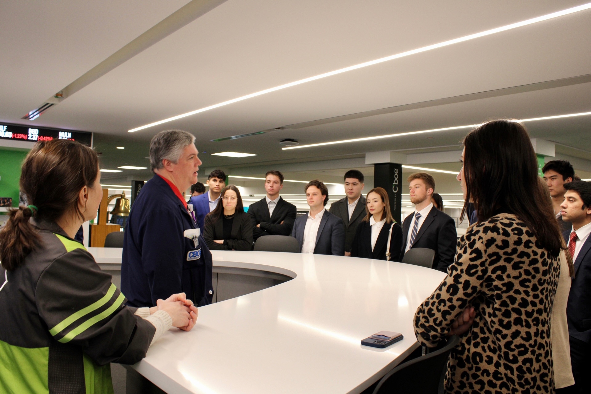 Illinois Wesleyan finance students stand around a counter speaking to a staff member with the Chicago Board Options Exchange