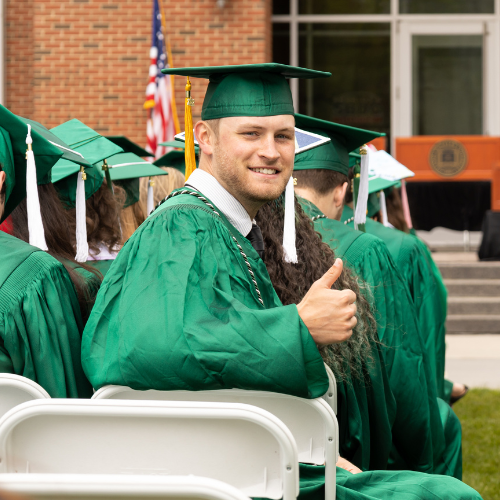 Student at commencement turned in seat to give thumbs up