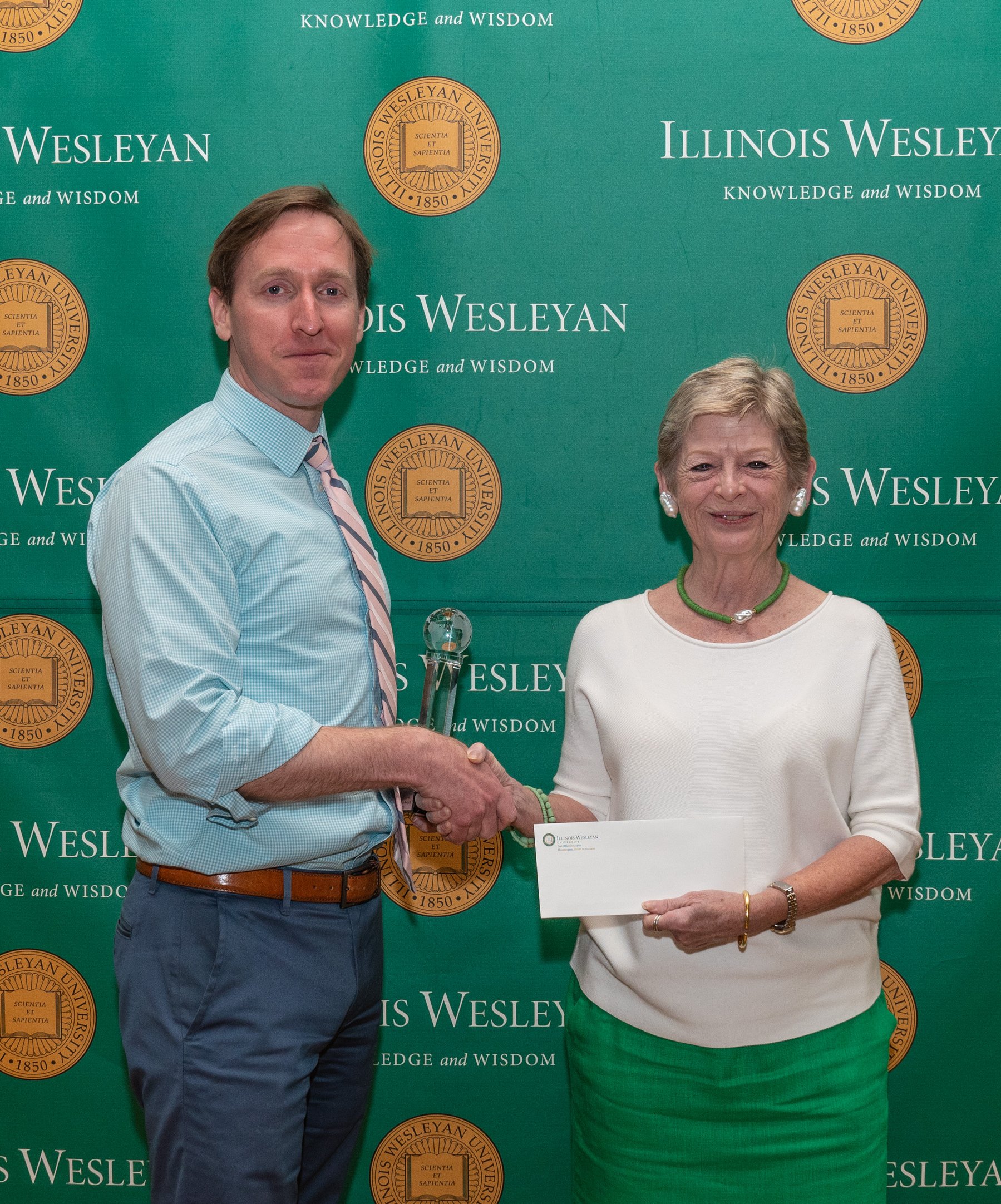 Kyle Griffith accepting award from IWU president Georgia Nugent