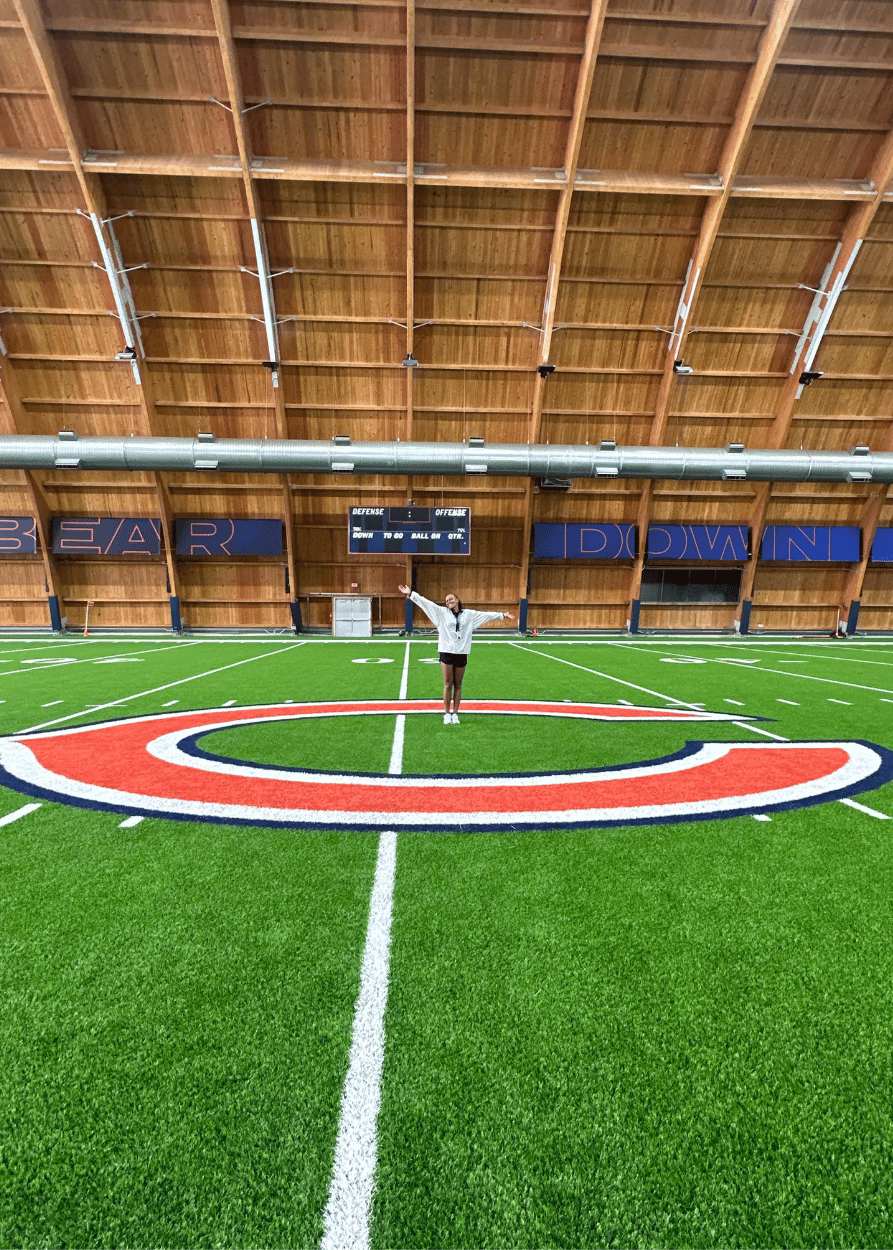 Taylor Tarver '24 stands in center field at the Chicacgo Bears training facility with a large C in the turf