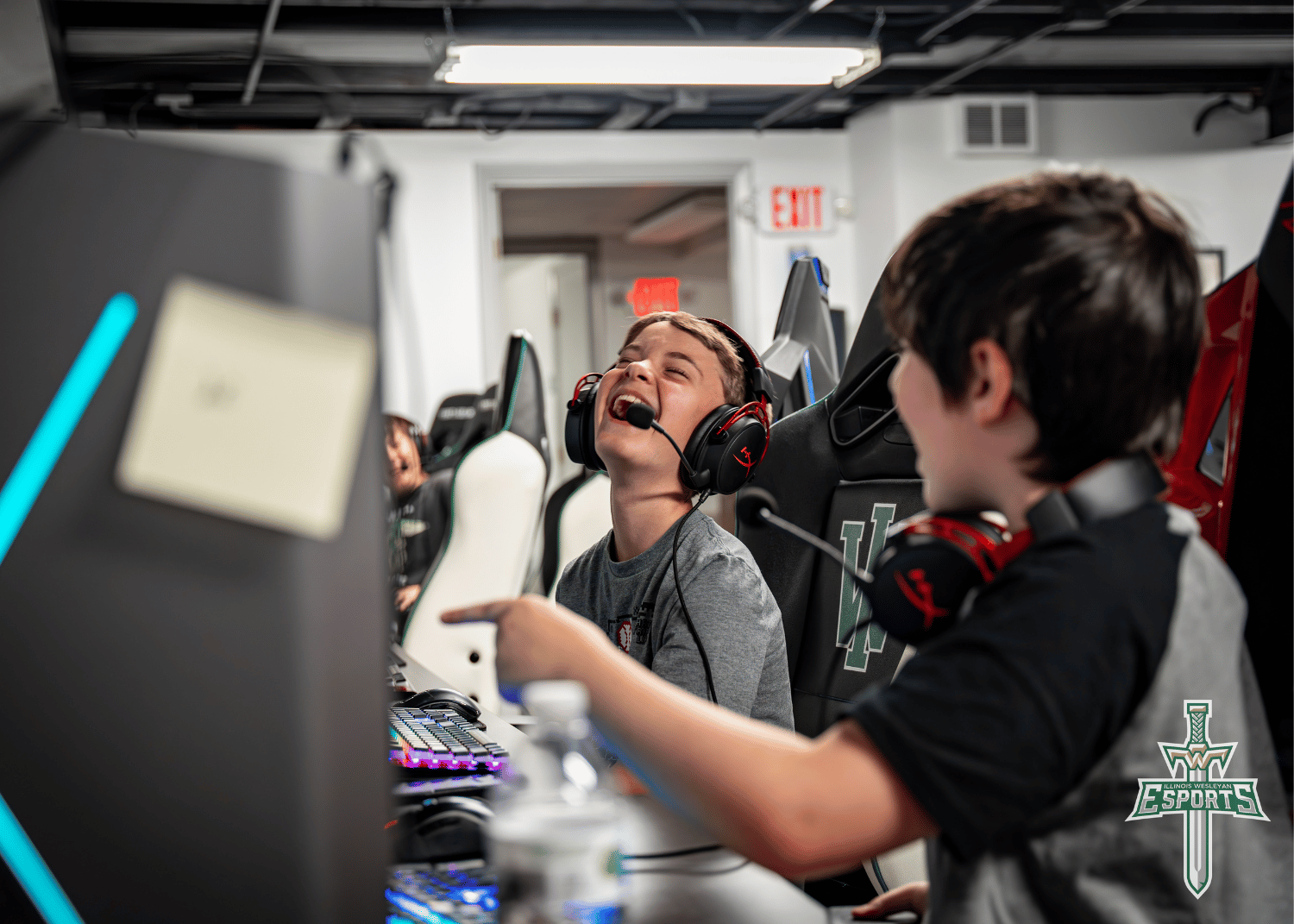 Children laugh together with headsets on as they play video games on computers in IWU's esports facility