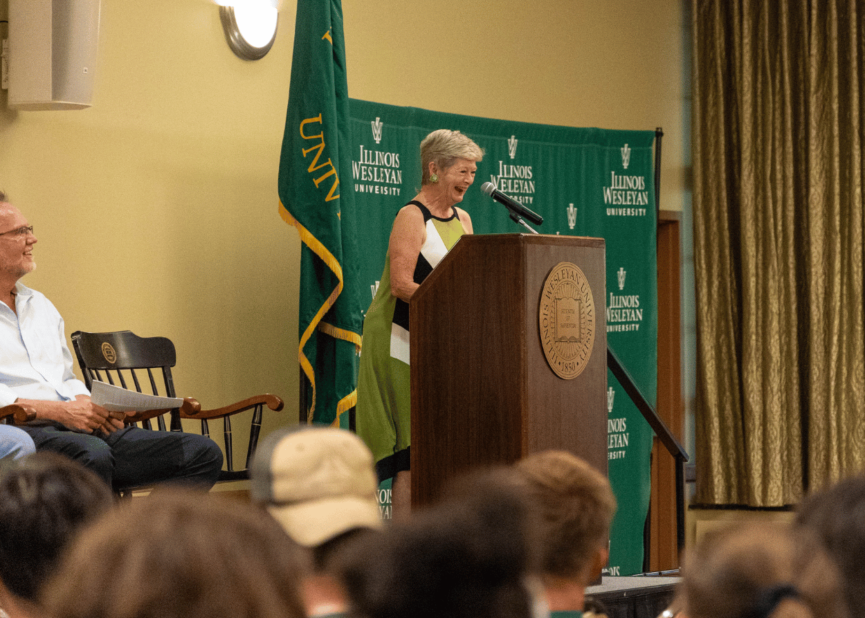 IWU President Georgia Nugent smiles from stage as she speaks to a crowd of students