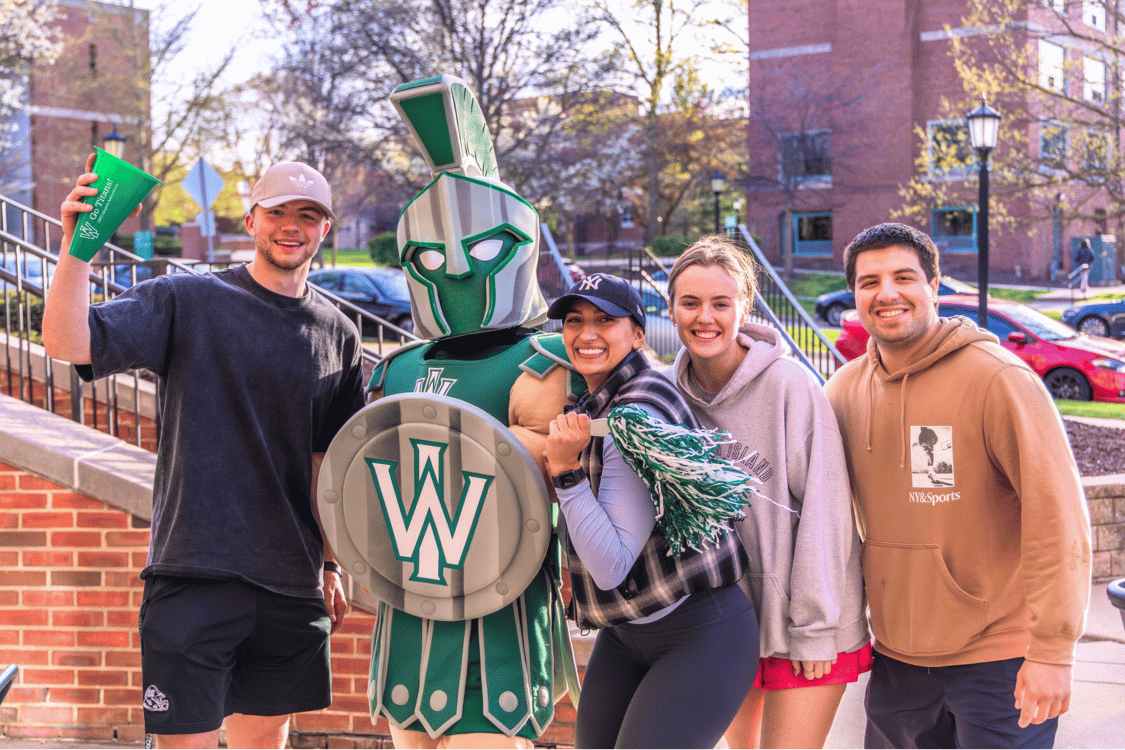 Three students wave pompoms with Tommy Titan mascot on IWU campus