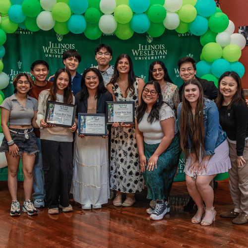 students posing with awards surrounded by balloons