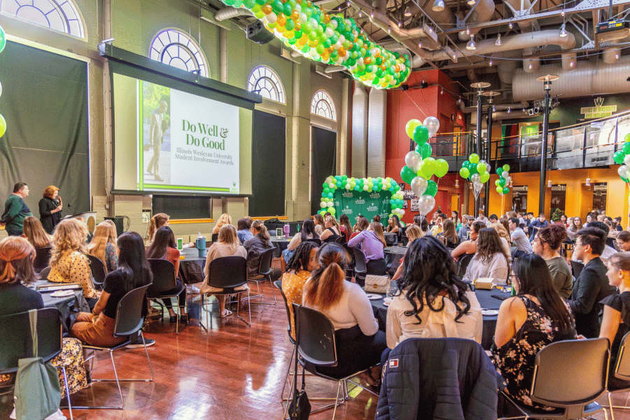 Students seated at tables surrounded by balloons during awards ceremony