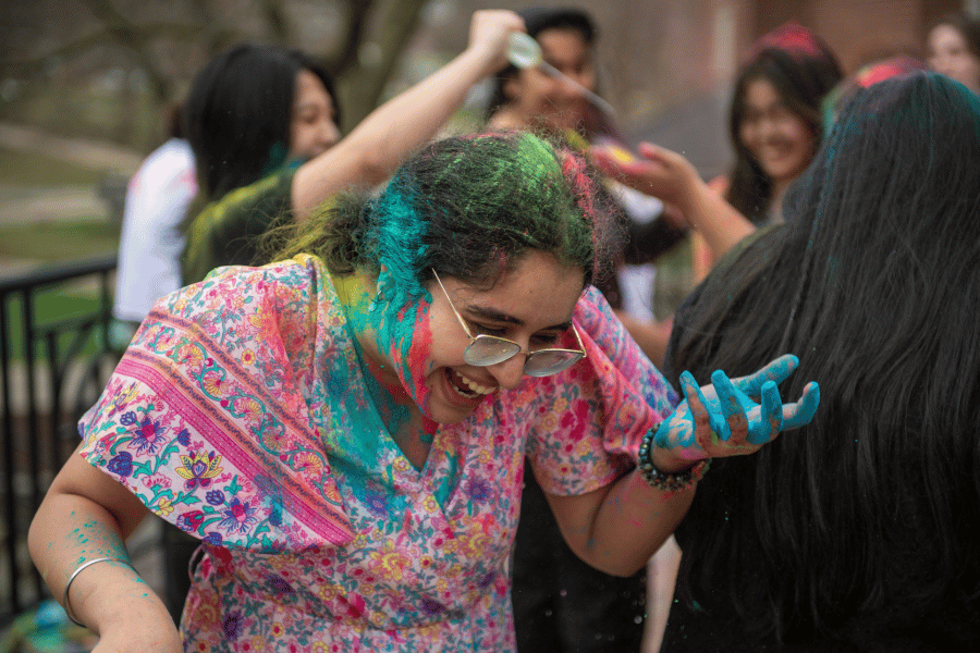 A student laughs, colored in colored powder, during a Holi celebration at Illinois Wesleyan
