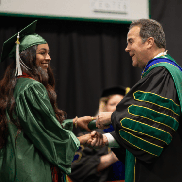 President Zenger shakes hand of graduate at commencement
