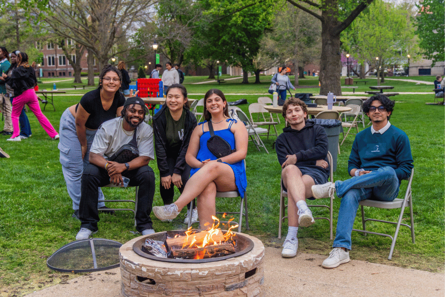 Students sit around bonfire on Eckley Quad at Illinois Wesleyan to celebrate end of the semester
