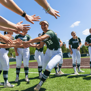 softball student athlete giving high fives to teammates on the field