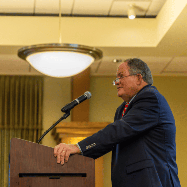 Ed Rust Jr speaking at a podium at Illinois Wesleyan
