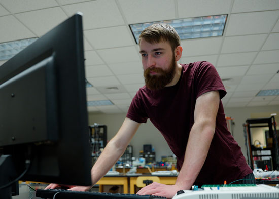 Ben Heinz at a computer in a physics lab