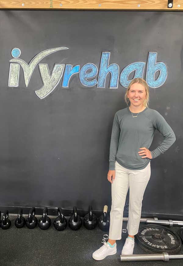 Lexi Onsrud stands in front of an Ivy Rehab sign at her internship