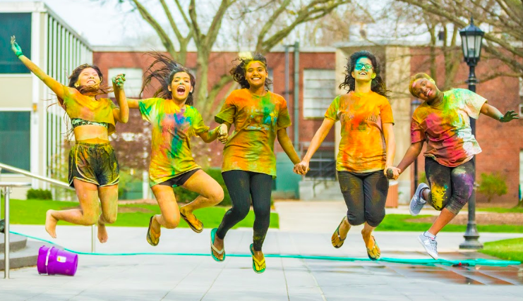 Five students participate in the Holi festival on the quad.