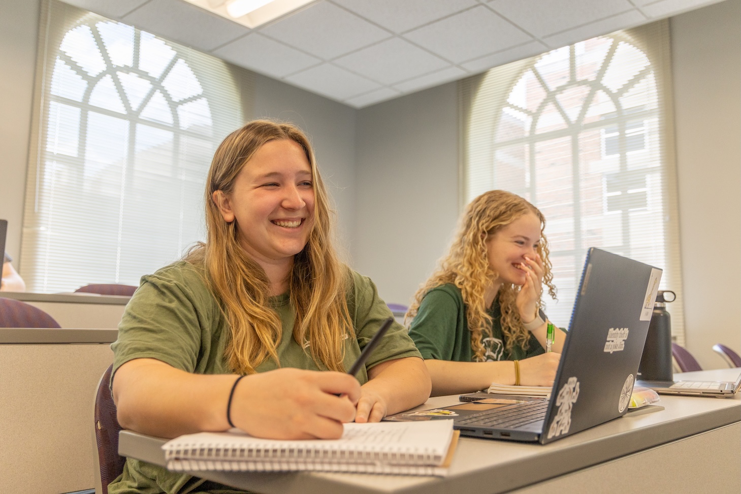 Two students smiling in a classroom.