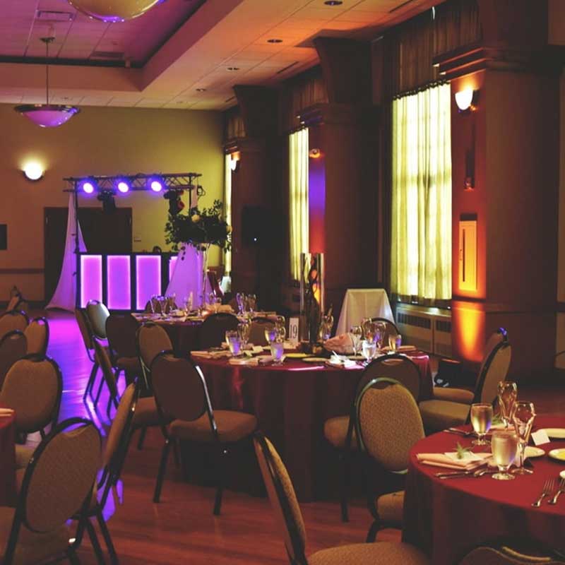 Round tables are spread out in Young Main Lounge, each topped with water glasses, place settings, and candles.